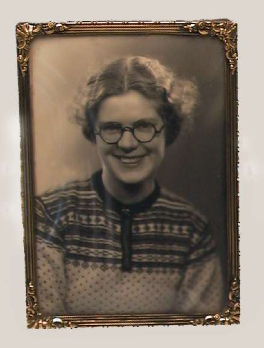 Gyllen metallramme med glass. Svart/hvitt fotografi av en ung dame med strikkegenser og runde briller.