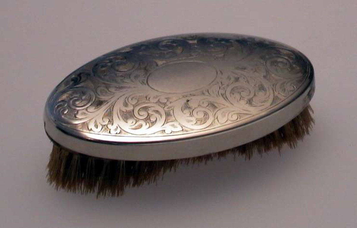 Oval børste med dekorert metallhode.