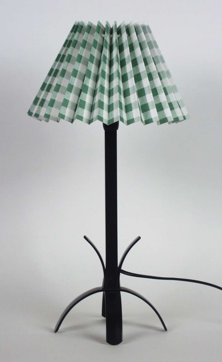 Bordlampe i svartlakkert metall. Skjermen er trukket med grønnrutet plissert bomullsstoff.