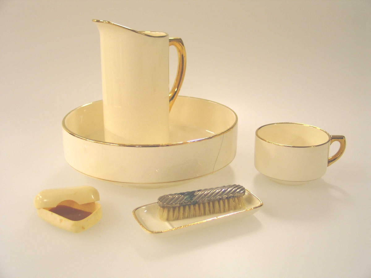 Såpeskål i dukkestørrelse i porselen med hank. Gulldekor øverst og på hanken. 