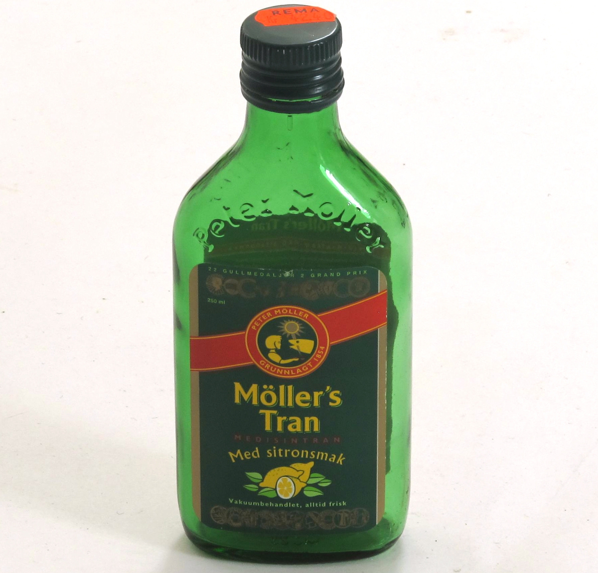 Flaske av grønnfarget glass, med grønn etikett, til  tran. 220 g.  Etikett med opplysninger om  innhold og oppbevaring, varemerke, utmerkelser og strekkode.