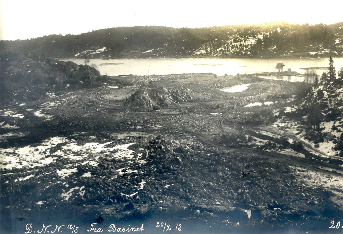 "20/02-1913" Nitriden. Fabrikktomten planeres.  Tromøysund og Tromøy i bakbrunnen. Fyrlykt nr. 612 i Norsk Fyrliste til høyre, bygd 1894, flyttet til Friisøy i 1929.