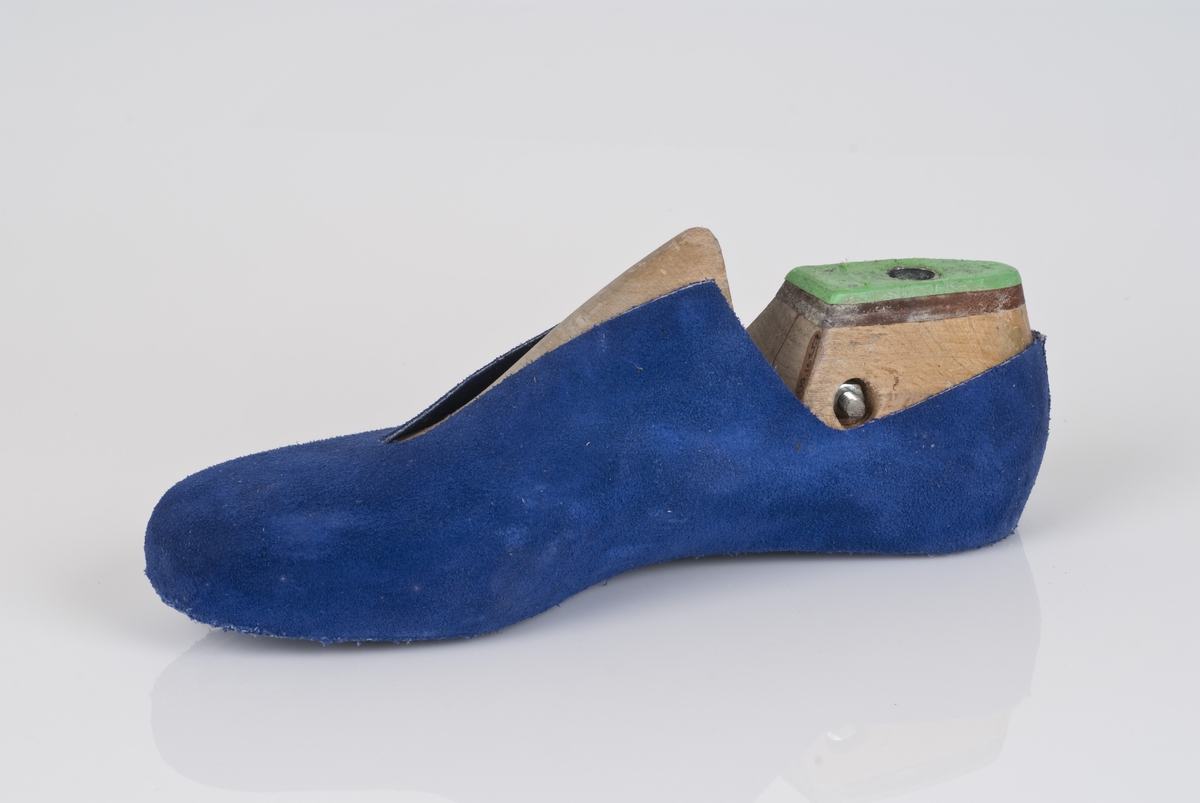 En trelest med overlæret til støvel (fabrikkstøvel).
Høyrefot i skostørrelse 44, med 7,5 cm i vidde.
Skinntrekket er i blåfarge.
Lestekam av plast i grønnfarge, og skinn.

