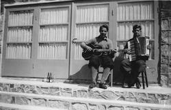 Gruppebilde. To menn spiller trekkspill og gitar.