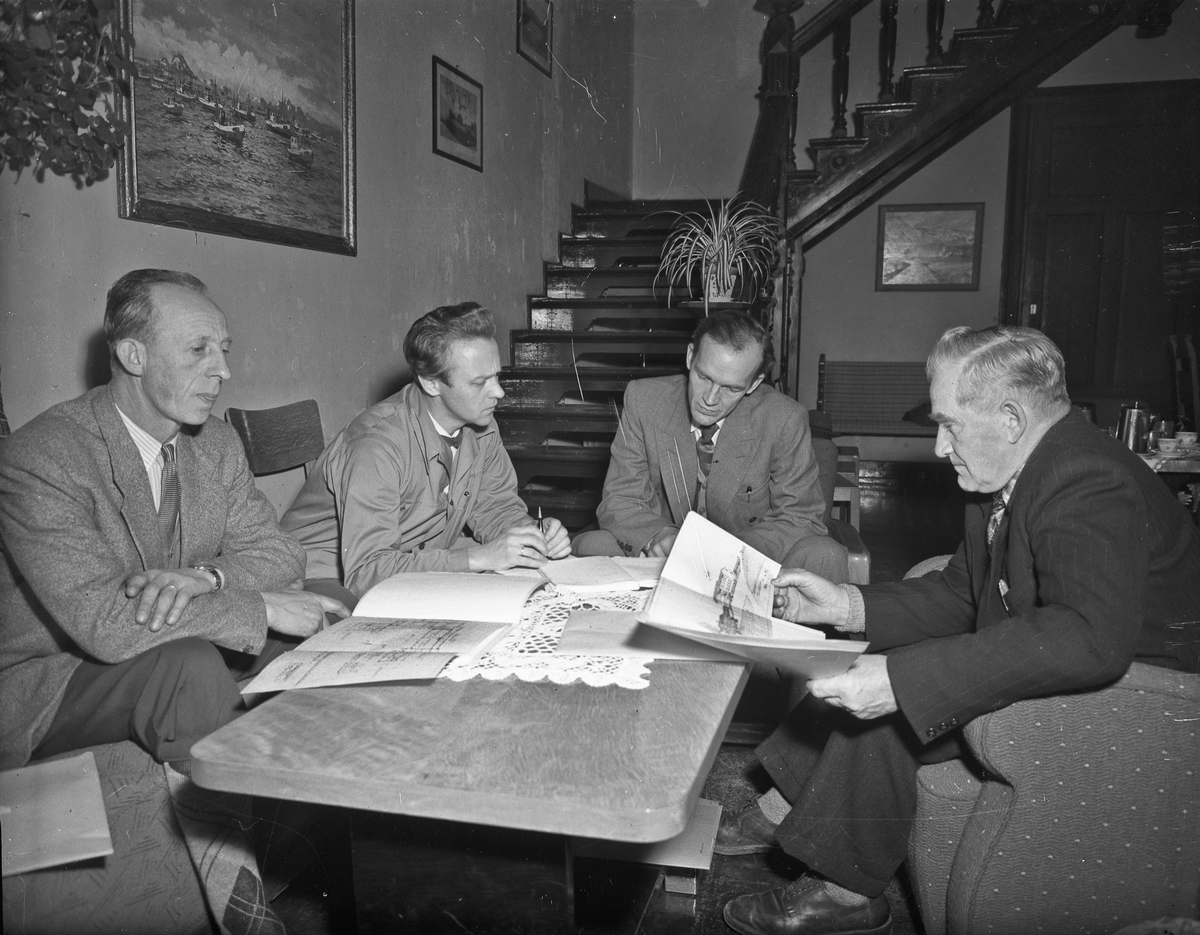 4 menn studerer papirer som kan se ut som byggetegninger. Erling Østerud til høyre(?). Kan være byggeprosjekt på Romerike Fylkesskole/Folkesskole.