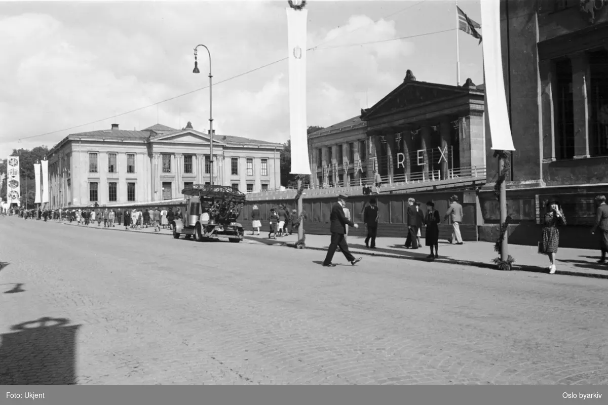 En pyntet Karl Johans gate ved Universitetet 7. juni 1945. Folkevandring mot Slottet. Teksten "VIVAT REX" (leve Kongen) opphengt på universitetsfasaden.