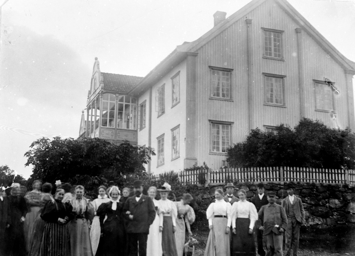Stor gruppe mennesker utenfor hovedbygningen på Hoel gård, Nes, Hedmark. Gardbruker Karl Kildal (1854-1915) med skalk, moren Marie Gotaas Kildal til venstre (1817-1900).