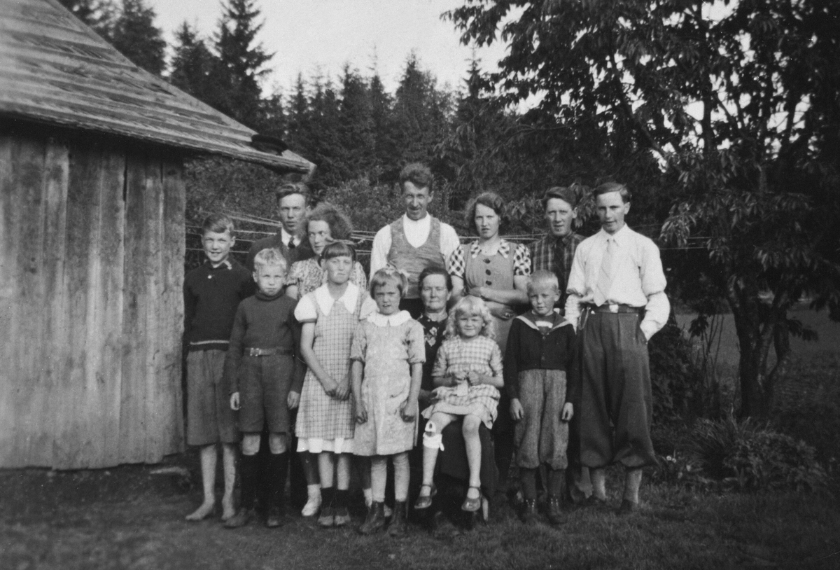 Einar Johansen (1895-1972) og hustru Lina Gulbrandsdatter Ringen (1888-1964) med 11 av sine 12 barn i Ordersveen, Aske østre, Nes, Hedmark. Bare Signe Othilie f.1918 som ikke er med. Einar var gardskar på Aske i alle sine arbeidsføre år. Ca. 1940.