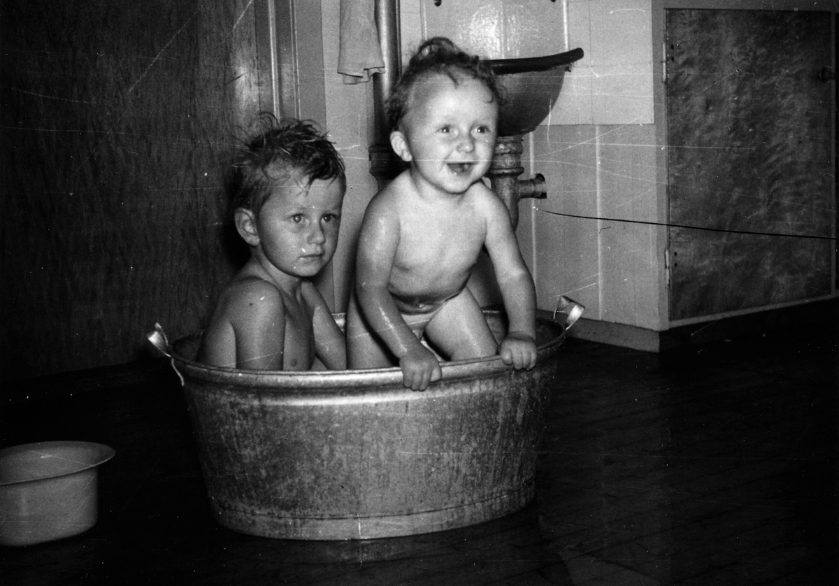 Interiør, Medlien gård, Ringsaker. Brødre i badebalje på kjøkkengulvet i 1959. Hans Christian (4) og Stein Roar (2).