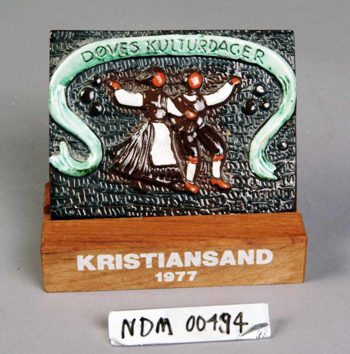 Relieff. Par i bunad danser folkedans under banner. Døves kulturdager Kristiansand 1977. 