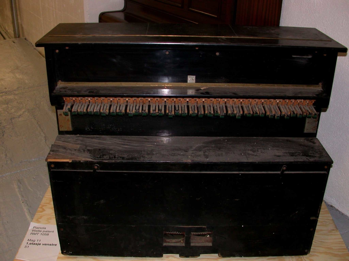 Kabinett med pianospiller for å plassere foran et ordinært piano. Omfang: CC-g’’’’  (80 toner)
Kabinettet er i svartmalt treverk. Apparatet er drevet av en elektrisk vakumpumpe. Pneumatisk dreven mekanikk, styrt av pianoruller med hull. Ved aktivering slår filtbekledde trefingrer ned på pianoets tastatur. To justerbare l-formete pedaler presser ned pedalene på pianoet. Høyden på instrumentet kan reguleres ved å bruke en sveiv i alle fire hjørnene.

To aksler for å feste pianorullen. Venstre aksel er en fast, ikke dreibar pigg (ø = 3,8), høyre aksling med hull samt to uttak for feste på pianorull (ø= 5, indre; 9 ytre). Pianorullen trekkes oppover over avleseren og festes på spolen (på andre pianospillere trekkes rullen omvendt, NEDOVER).

Pneumatisk avleser med undertrykk, såkalt tracker bar med 100 hull, 8 hull/tomme, tot 12 7/8 tomme bred. Hull nr. 1-10 er funksjonshull, 11-90 aktiverer tonene CC-g’’’’ og 91-100 er funksjonshull. Funksjonene er fra venstre: (1-2) Bass mezzoforte (normalstyrke) på respektive av; (3-4) bas crescendo på og av, (5-6) sfz (accent) i bass på og av, (7-8) piano pedal ned respektive opp samt (9-10) normal eller snabb motorhastighet. (91) tillbakespolning, (92) ikke brukt hull (!), (93-94) fortepedal på og av, (95-96) sfz ( accent) i diskant på og av, (97-98) crescendo i diskant på og av samt (99-100) mezzoforte (normalstyrke) for diskantside (Reblitz 2001:372)

Spak til høyre i rom for reglasjer, leder til liten belg. Uklar funksjon.

Av funksjonshullene fremgår at det er flere ulike muligheter til automatisk dynamisk variasjon (crescendo/diminuendo, accenter og bruk av pedal).  Instrumentet har i tillegg to reglasjer i rommet for pianoruller: til høyre for å variere tempo i tre trinn; til venstre for å reversere/spolle rullen tilbake. Der er også et hull for påfyll av olje.