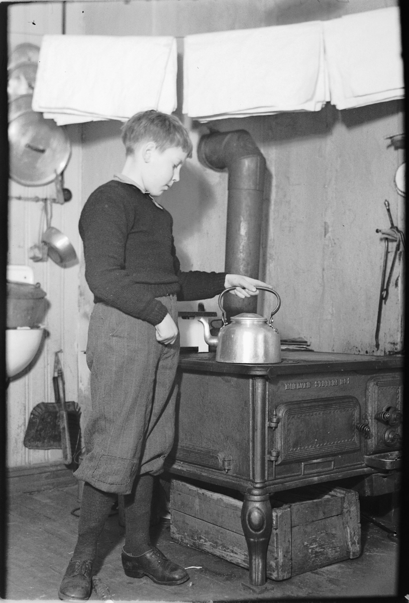Ringsaker, Moelv, Ole Christian Prestkværn (1937-1983) koker kaffe på ovn, komfyr produsert ved Moelv støperi. Interiør fra kjøkkenet på Løkkekværn Gård,