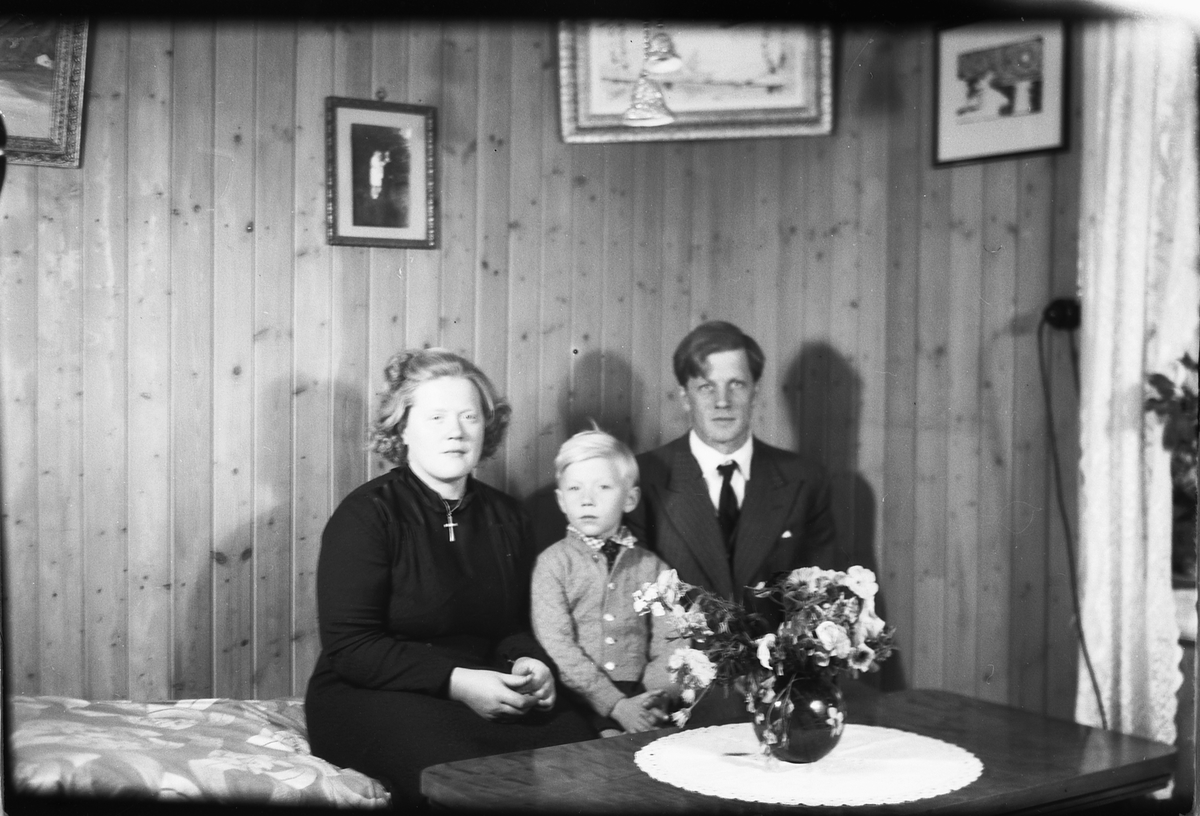 Interiør, stue. Astrid, Birger og Olav Aamodt sittende på en sofa. 