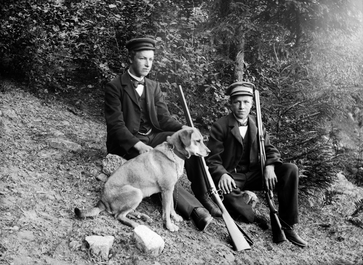 To menn på jakt med gevær og hund. 