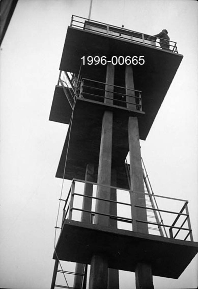 Tårnet på Rafjell skogbrannvakstasjon, øst for innsjøen Nugguren i Brandval, Hedmark.  Tårnet ligger 585 meter over havet.  Det ble bygd 1934 etter initiativ fra det kommunale skogrådet i Brandval og med økonomiske bidrag fra forsikringsselskapet Skogbrand.  Eier var Brandval kommune, som seinere er sammenlått med Kongsvinger.  Tårnet er utført i armert betong og står på ei bergflate. Det har fire loddrette bein eller pilarer som gir tårnet et rektangulært grunnplan, der det etter fotografiet å dømme inngår et rektangulært rom med inngang i den ene kortenden.  Adkomsten til utkikksstedet på toppen skjer via jernstiger og to plattformer med jernrekkverk, den nedre er støpt rundt to av pilarene, den øvre rundt alle fire.  På toppen står ei rektangulær utkikkshytte på en noe utkraget plattform med jernrekkverk.  Fotografiet er tatt fra en posisjon tett inntil tårnfoten oppover mot utkikkshytta.  Der står en mann ved rekkverket foran hytta. 

Rafjelltårnet var bemannet i tørkeperioder sommerstid og inngikk i den regionale brannberedskapen i regionen fram til og med 1977-sesongen.  Kommunene Brandval, Vinger og Grue bidro til å finansiere dette tilsynet.  I 1935 ble det laftet ei tømmerhytte like ved tårnet, som overnattingssted for brannvaktene.  Fra og med 1978 overtok småflyentusiaster skogbranntilsynet.  Vakthytta ble ødelagt ved en brann i 1982.  Femten år seinere fikk Hokåsen utmarkslag laftet ei ny hytte med tanke på friluftsfolk som har Rafjellet som turmål.  Etter at skogbrannvaktholdet fra Rafjellet oppførte fikk tårnet i 1980 en ny funksjon som «mast» for politiets, tollvesenets og Røde Kors’ radiokommunikasjon.  Mange innså at brannvakttårnet var et interessant kulturminne, men det var uklart hvem som hadde vedlikeholdsansvar.  Tidlig på 2000-tallet anslo et ingeniørfirma at tårnet hadde et oppussingsbehov som ble kalkulert til 230 000 kroner.  Tiltak ble iverksatt med midler fra flere instanser, men med Kongsvinger kommune som hovedbidragsyter.