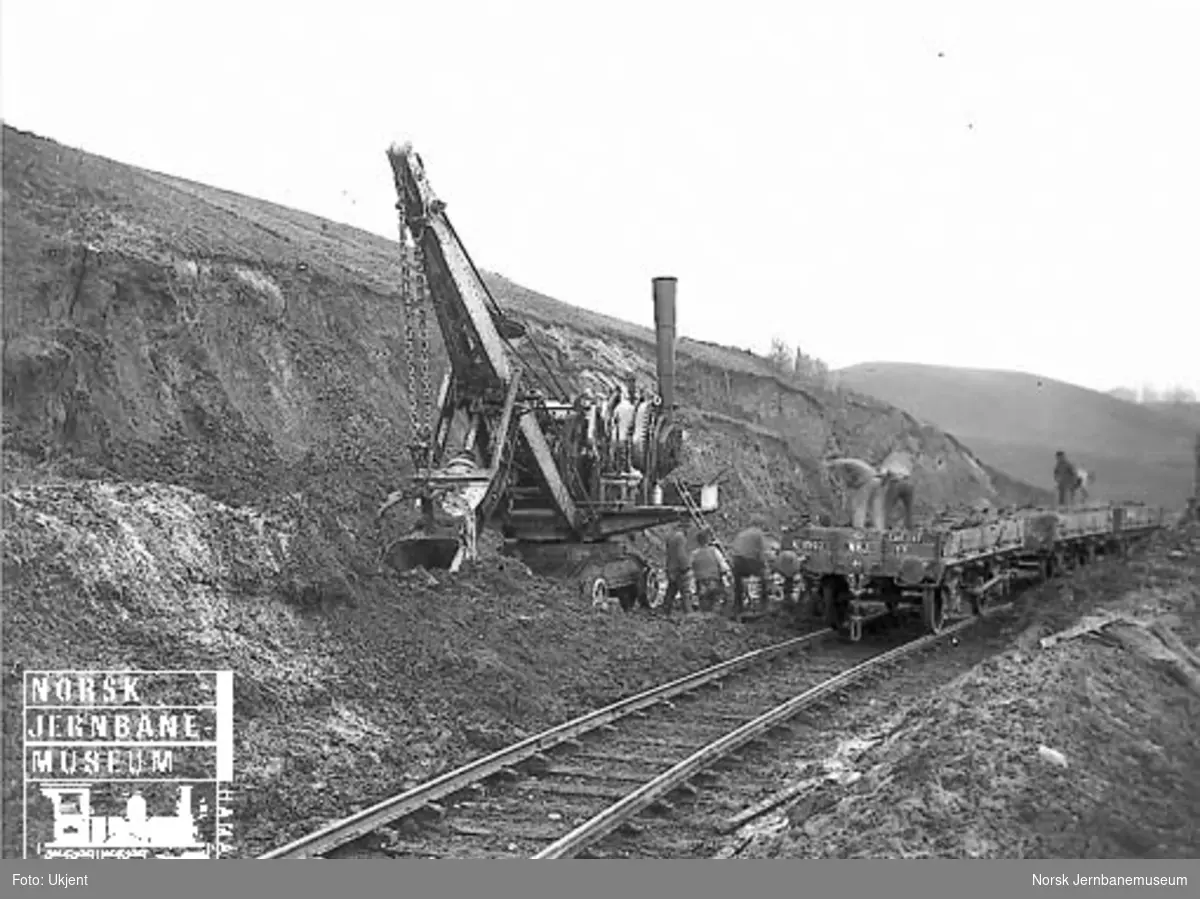 Opplasting av fyllmasse til Lillestrøm stasjons utvidelse med skinnegående gravemaskin - Excavator