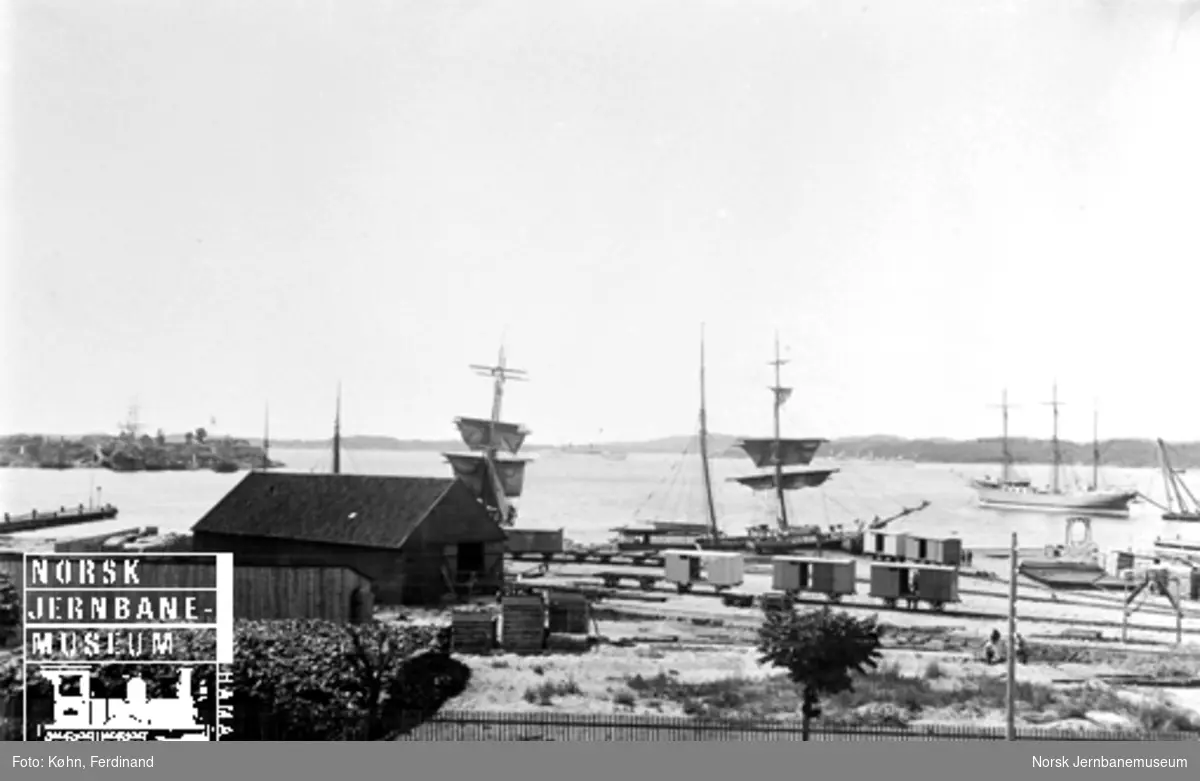 Jernbanens byggetomt i Kristiansand med godsvogner under sammensetning og i bakgrunnen seilskuter