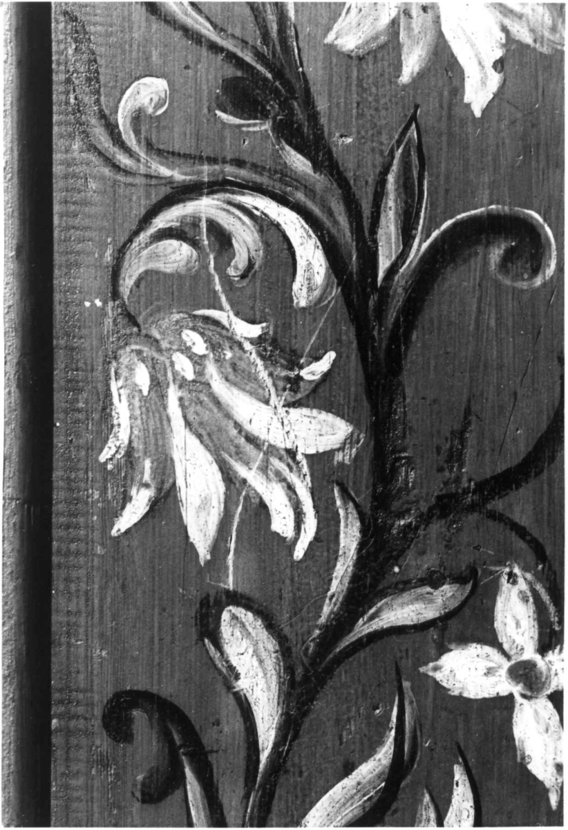 Skap i over- og underdel. Ovedelen har skjehylle og plass til skuffer. Buet topplist satt sammen av vinkelskårete deler. Blomstermalt.