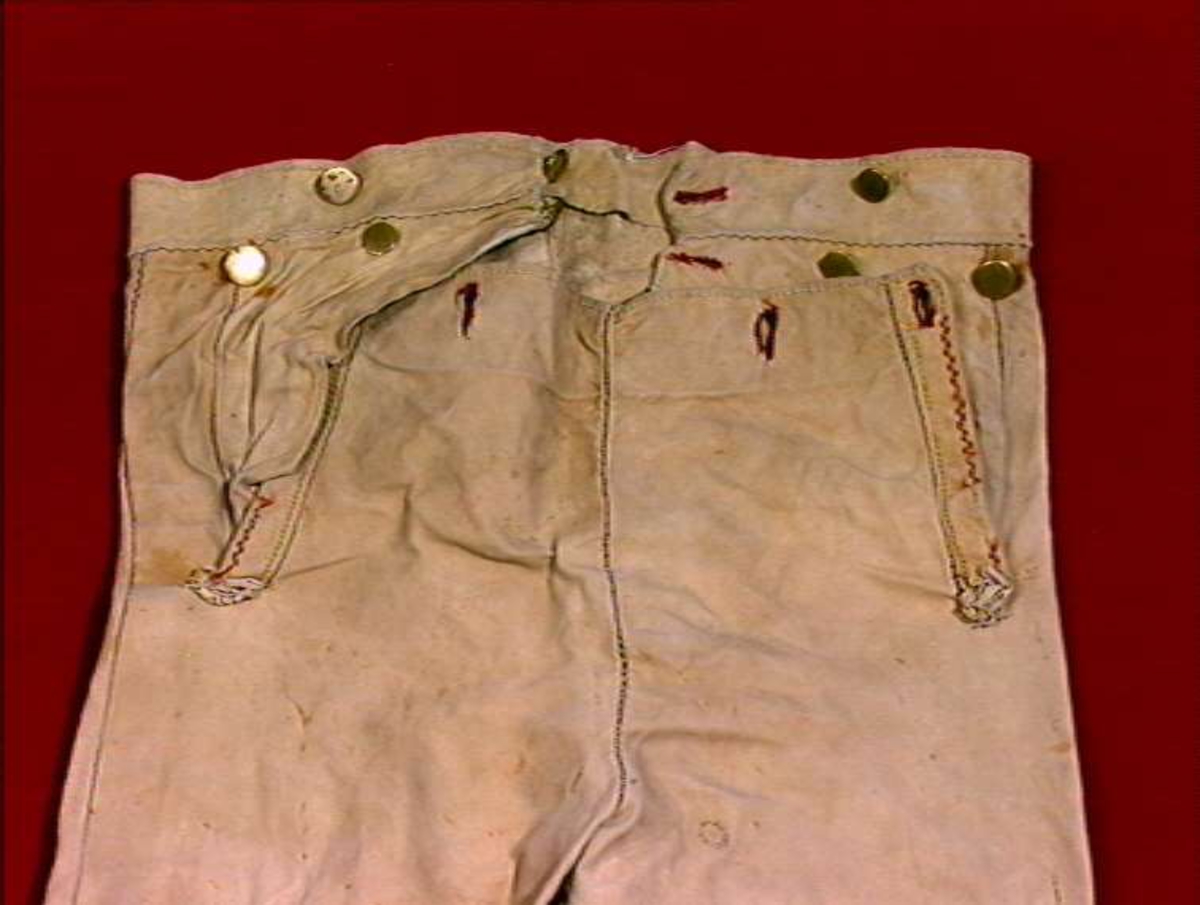 Skinnbukser med brodert dekorasjon fram og på ben. Messing og sølvknapper.