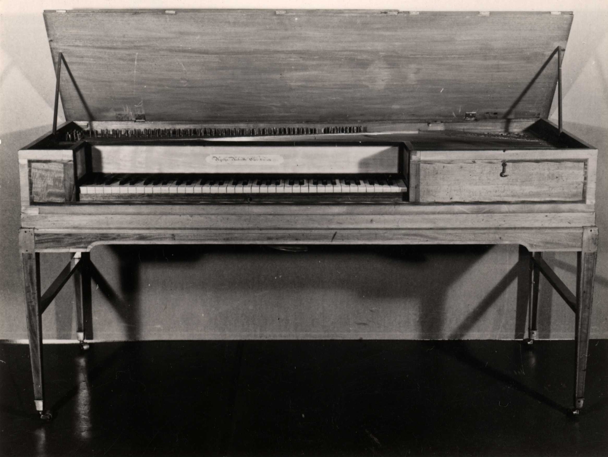 Taffelpiano av mahognifiner, firkantet kasse med innsnitt for klaviaturet, 5½ oktav F'–c''''. Understell med to par firkantede ben forbundet med tverrstang, knepedal. Første eiers navn med datering på frontplate, firmamerke med datering på klangbunn.