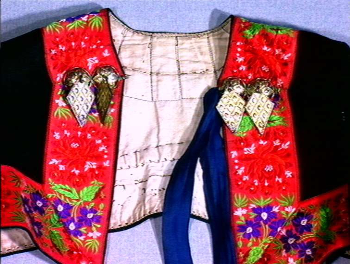 Svart trøye av klede med dekor av silkebånd, fløyel og sølv spenne.