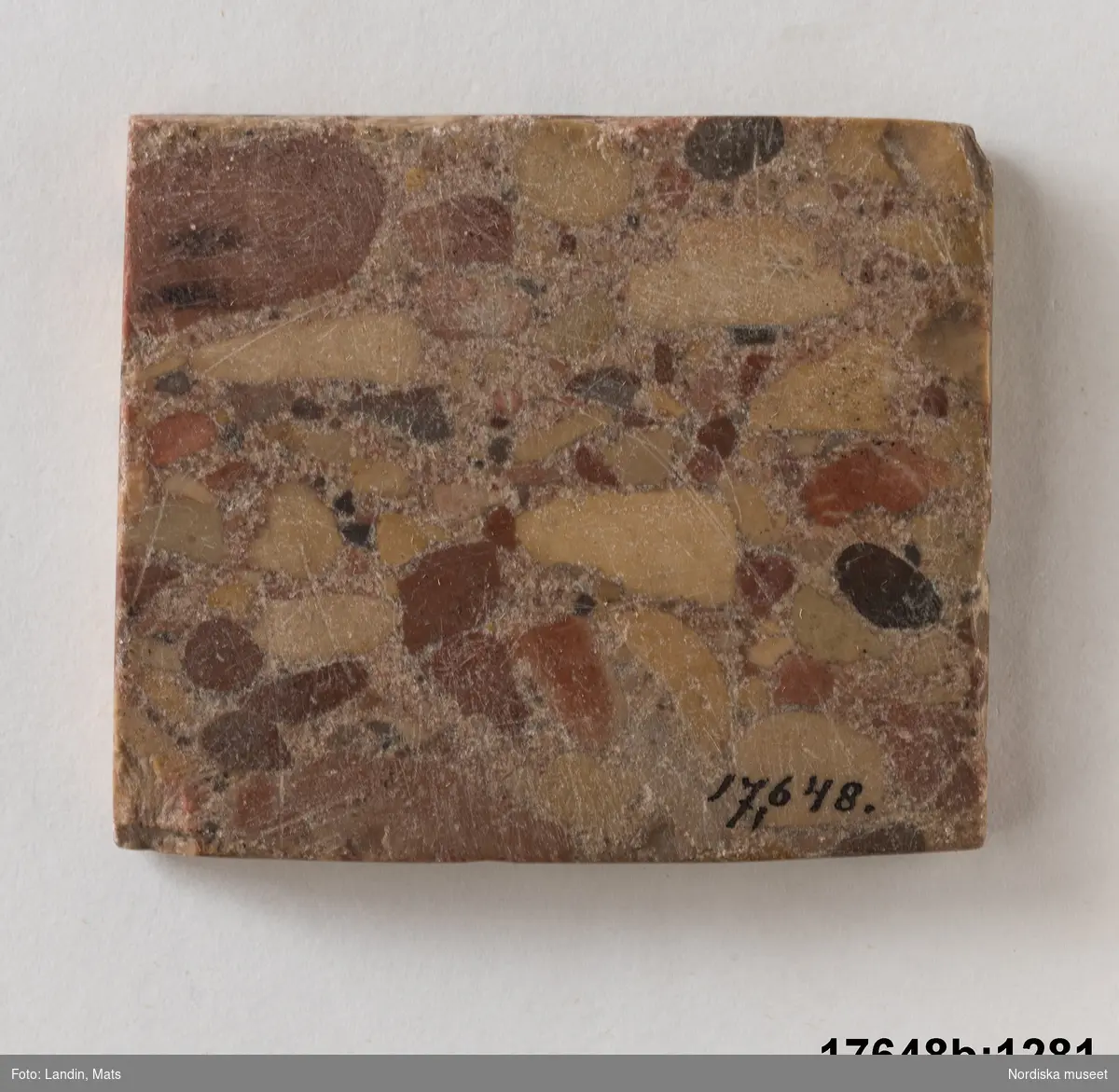 Rektangulär platt sten (marmor?), marmorerat mönster i olika matta nyanser. 
/Leif Wallin 2014-01-07