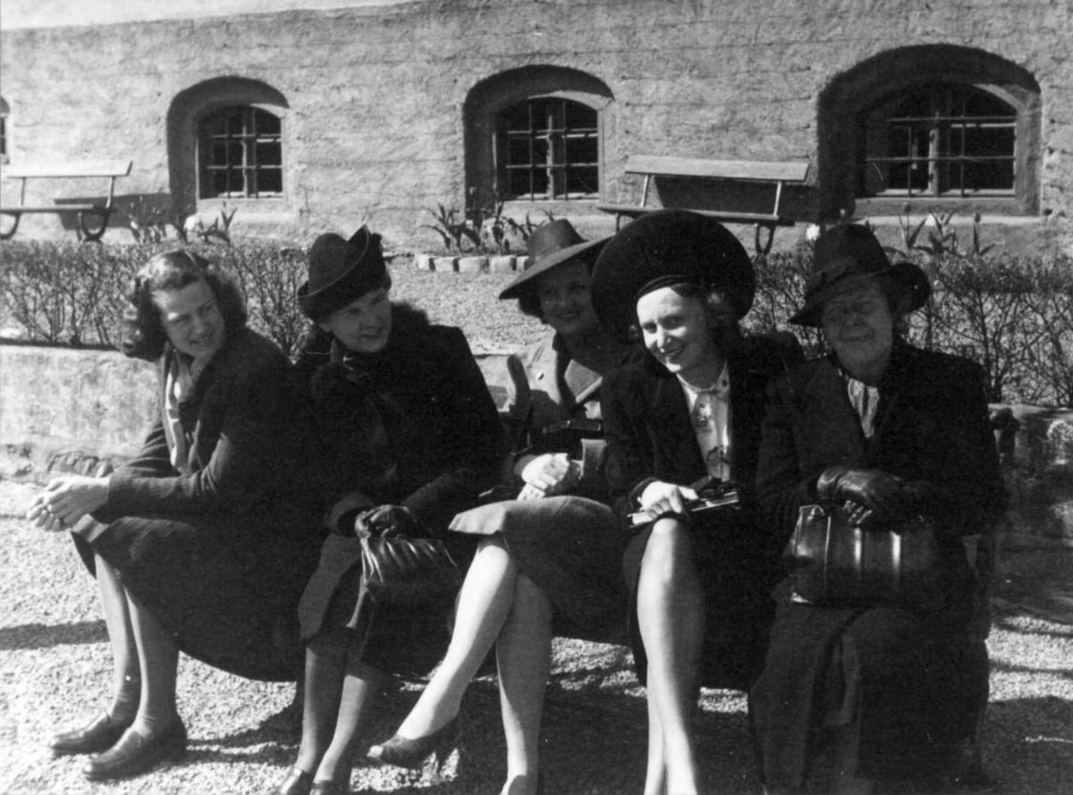 Fem av museets kvinnelige ansatte på en benk i solveggen foran Bybygningen, bygning nr. 311, 3.mai 1946.
