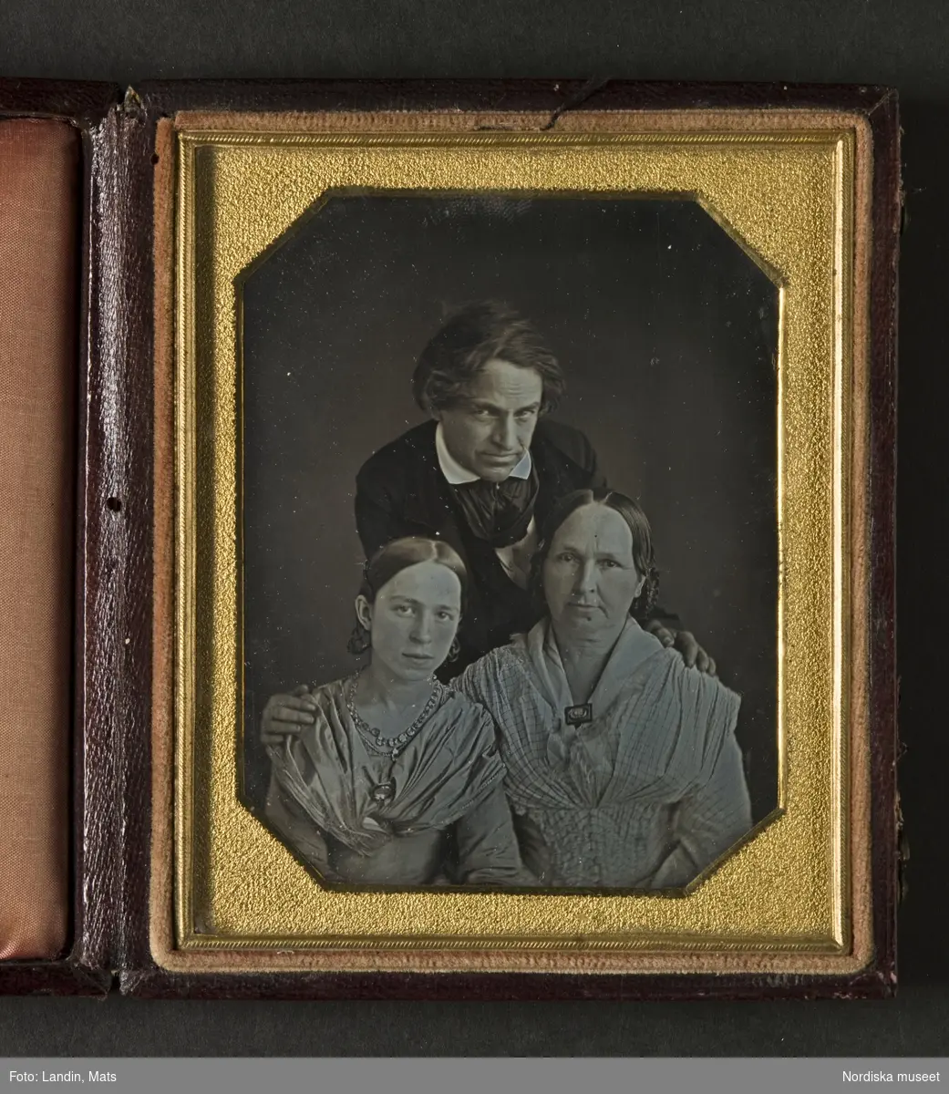Familjeporträtt av man, hustru och dotter.