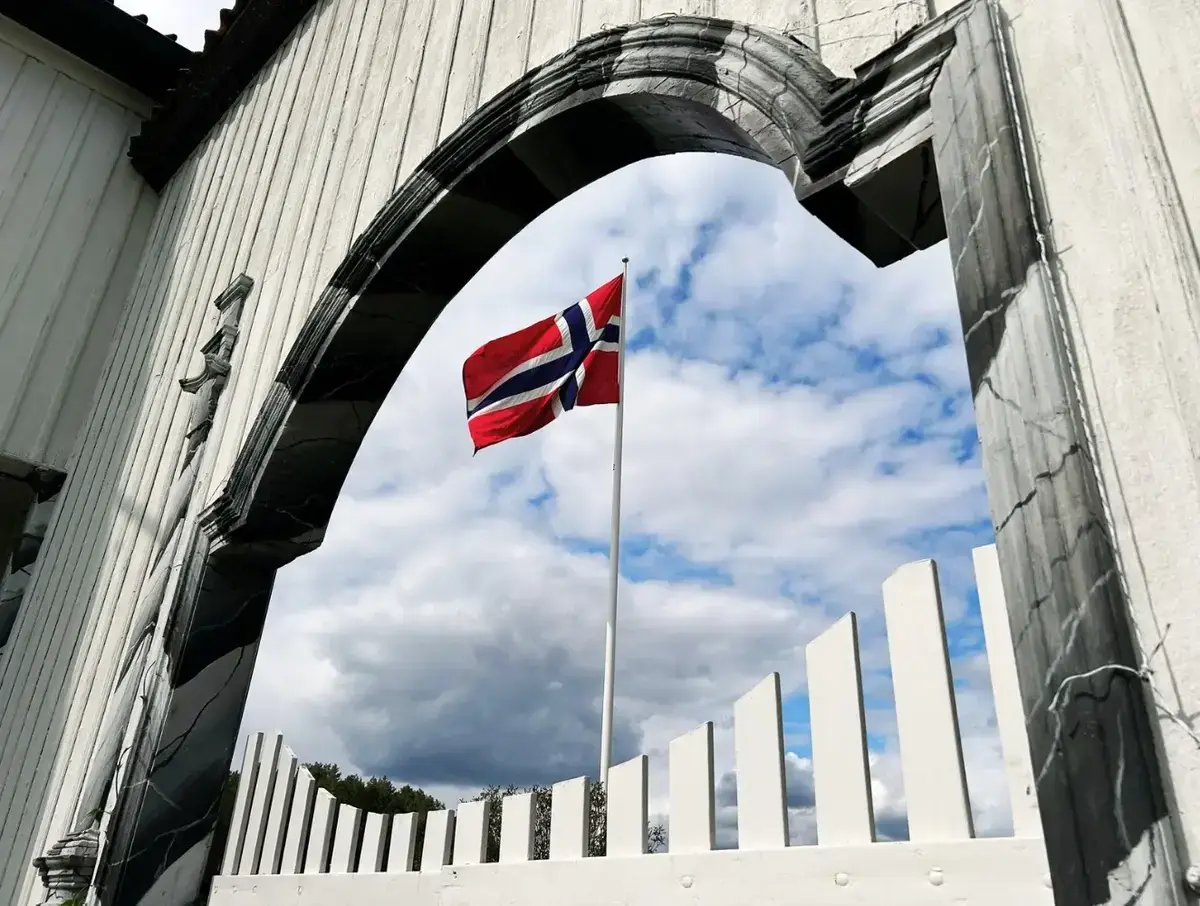 Vaiende norsk flagg sett gjennom hovedporten på Fossesholm Herregård